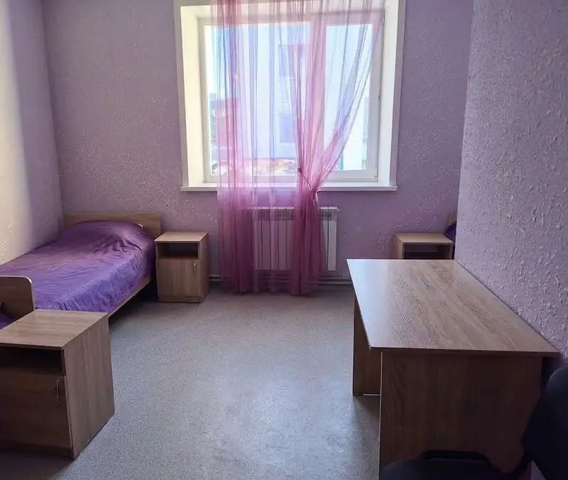 Комната в VIP-квартире: кровати, тумбочки и письменный стол у окна
