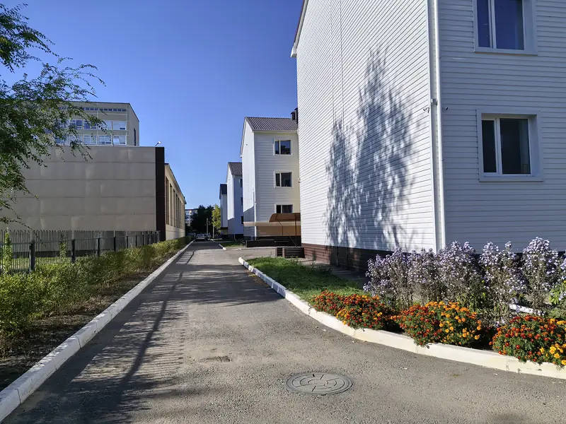 Дорожка между корпусами, клумбы вдоль стены