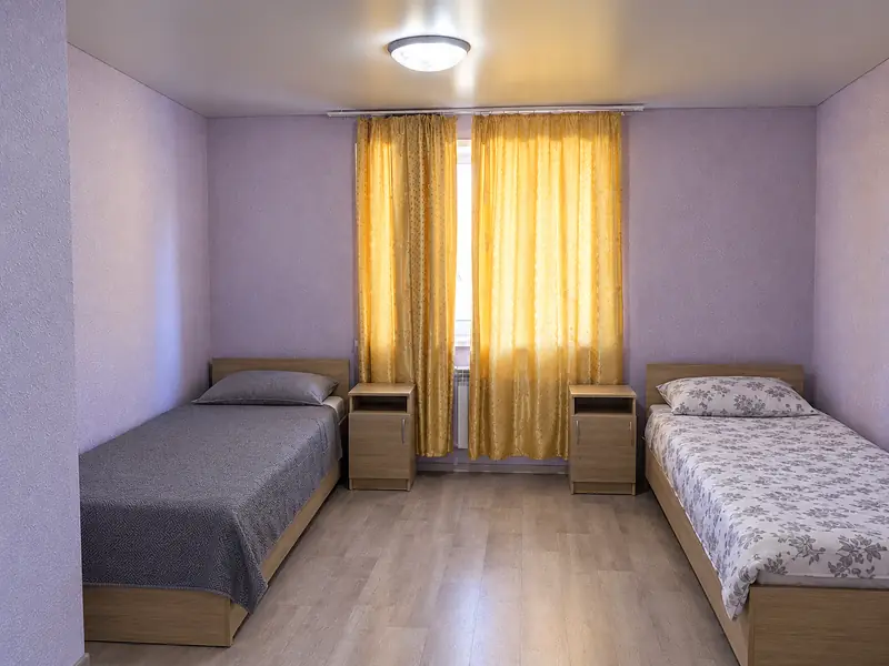 Комната на четверых: кровати, тумбочки и большое окно